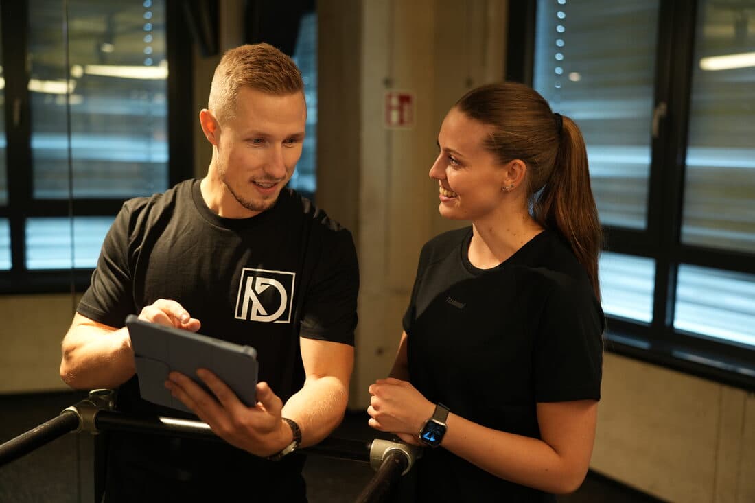 Dietmar Kühnel bespricht den Trainingsplan auf dem Tablet mit einer Trainierenden.